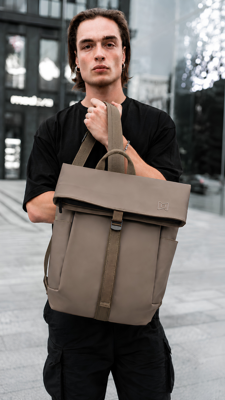 The Outpost Roll-Top Backpack in Beige carried by the top handle #Color_Beige