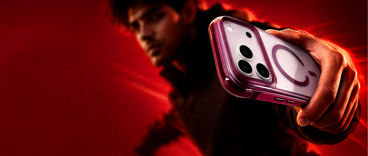 A person in a dark outfit holds up a smartphone with a translucent pink case against a dramatic red-lit background.